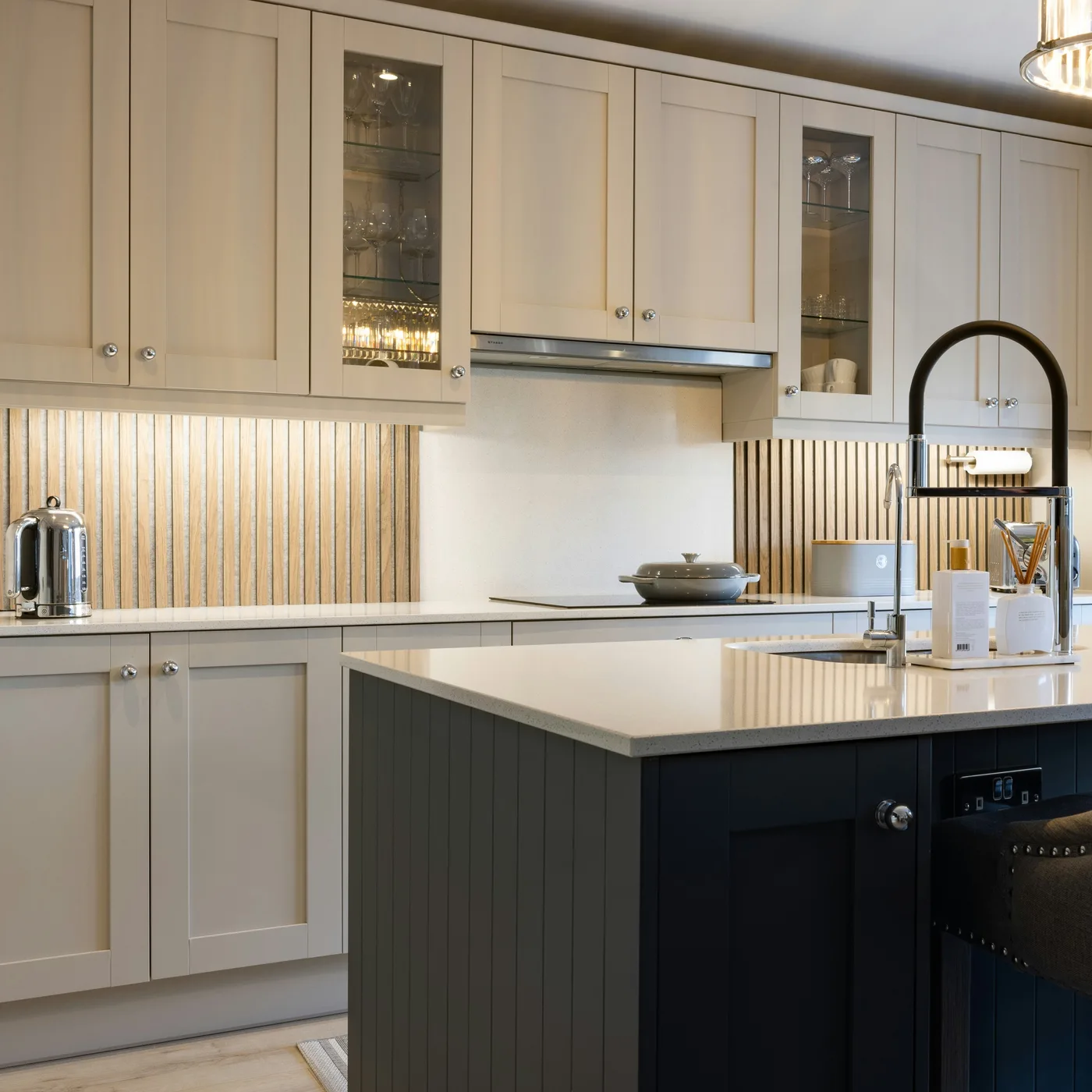 A kitchen with cream Shaker units and a dark painted island